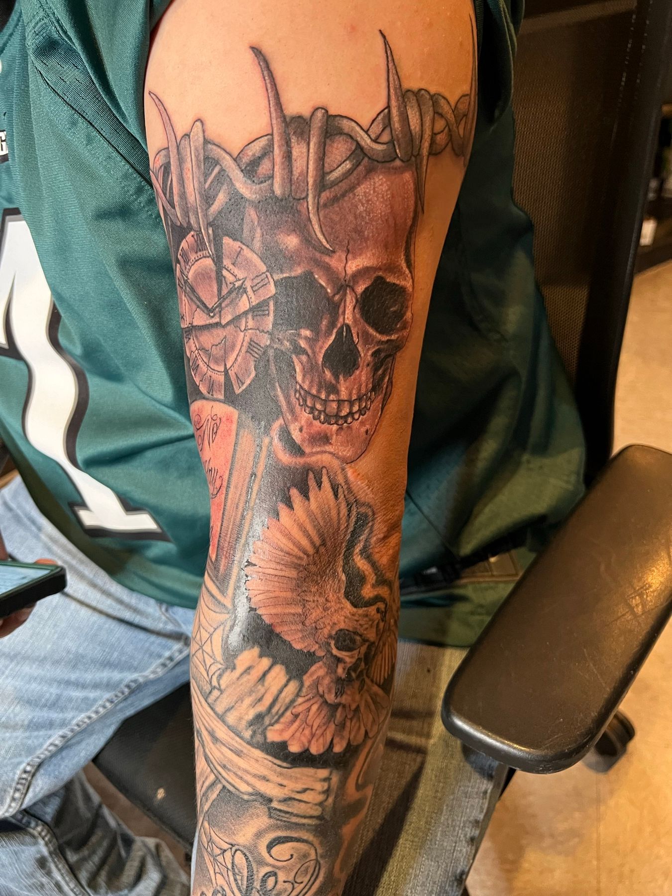 Close-up of the healed black and grey skull, barbwire, and pocket watch forearm cover-up at American Ink in Sherman Oaks.