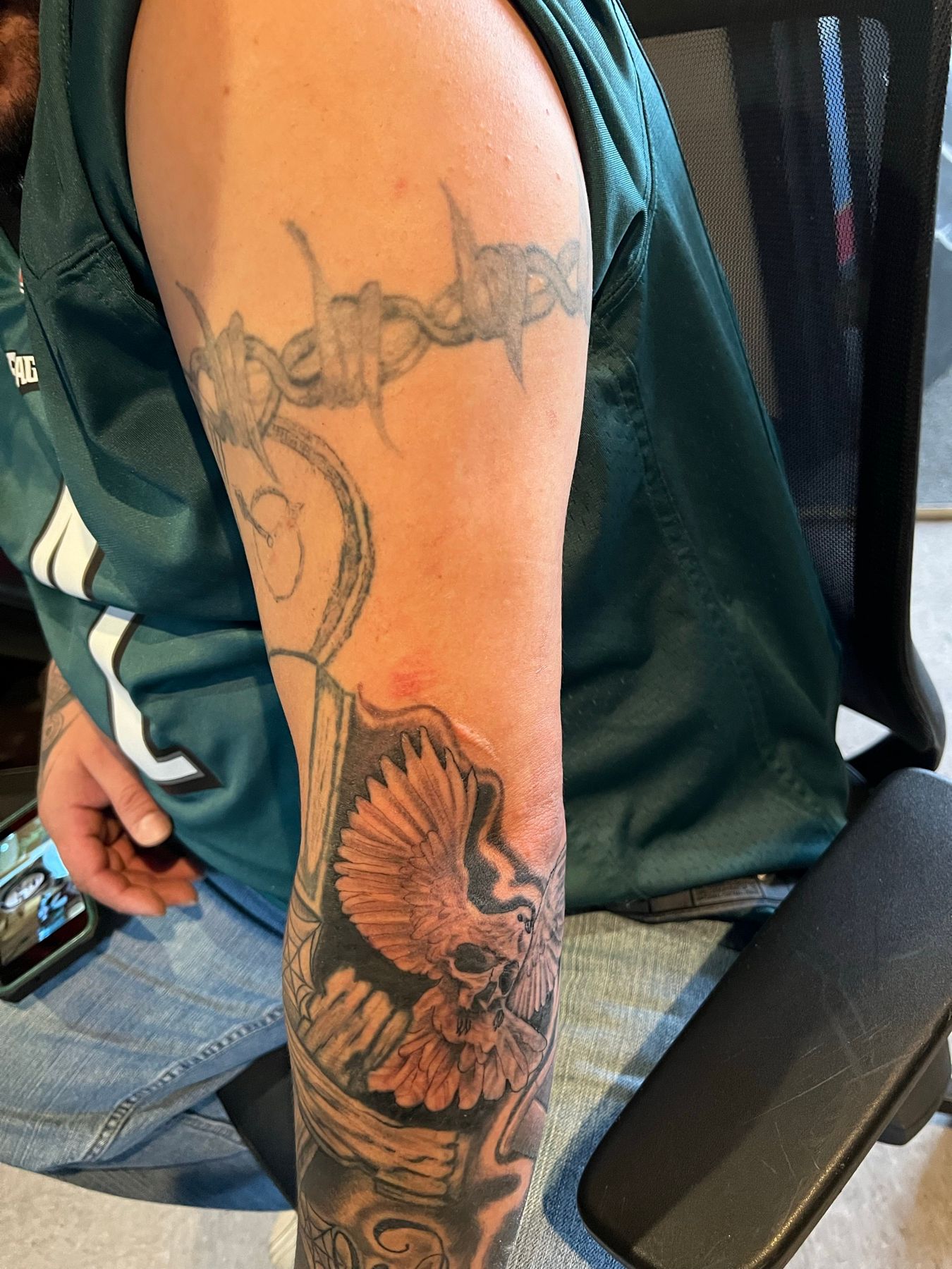 Faded barbwire and snake forearm tattoo with the new black and grey cover-up already started below it, at American Ink in Sherman Oaks.