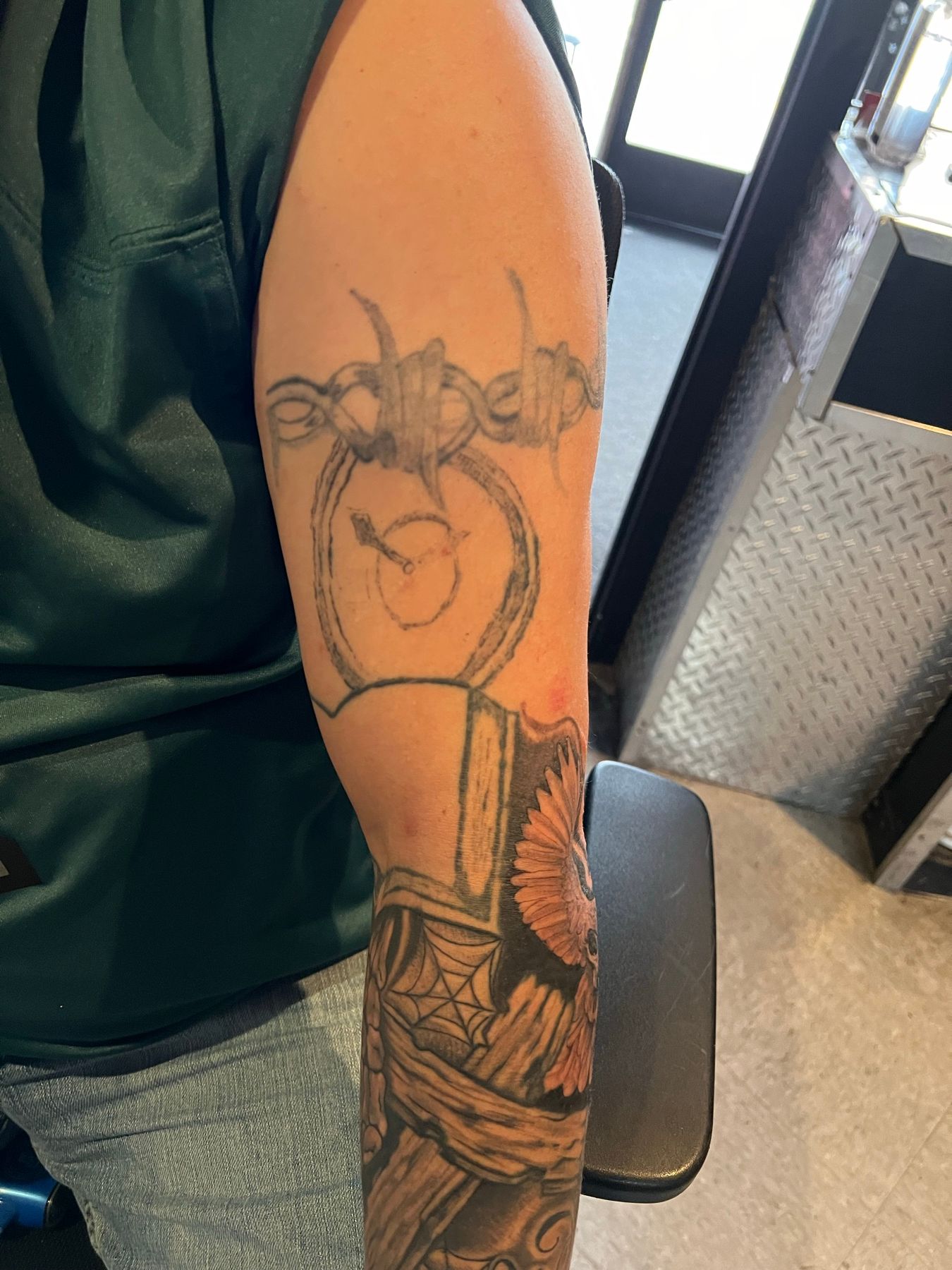 Old, faded forearm tattoo of a snake wrapped around a dagger before its cover-up at American Ink in Sherman Oaks.