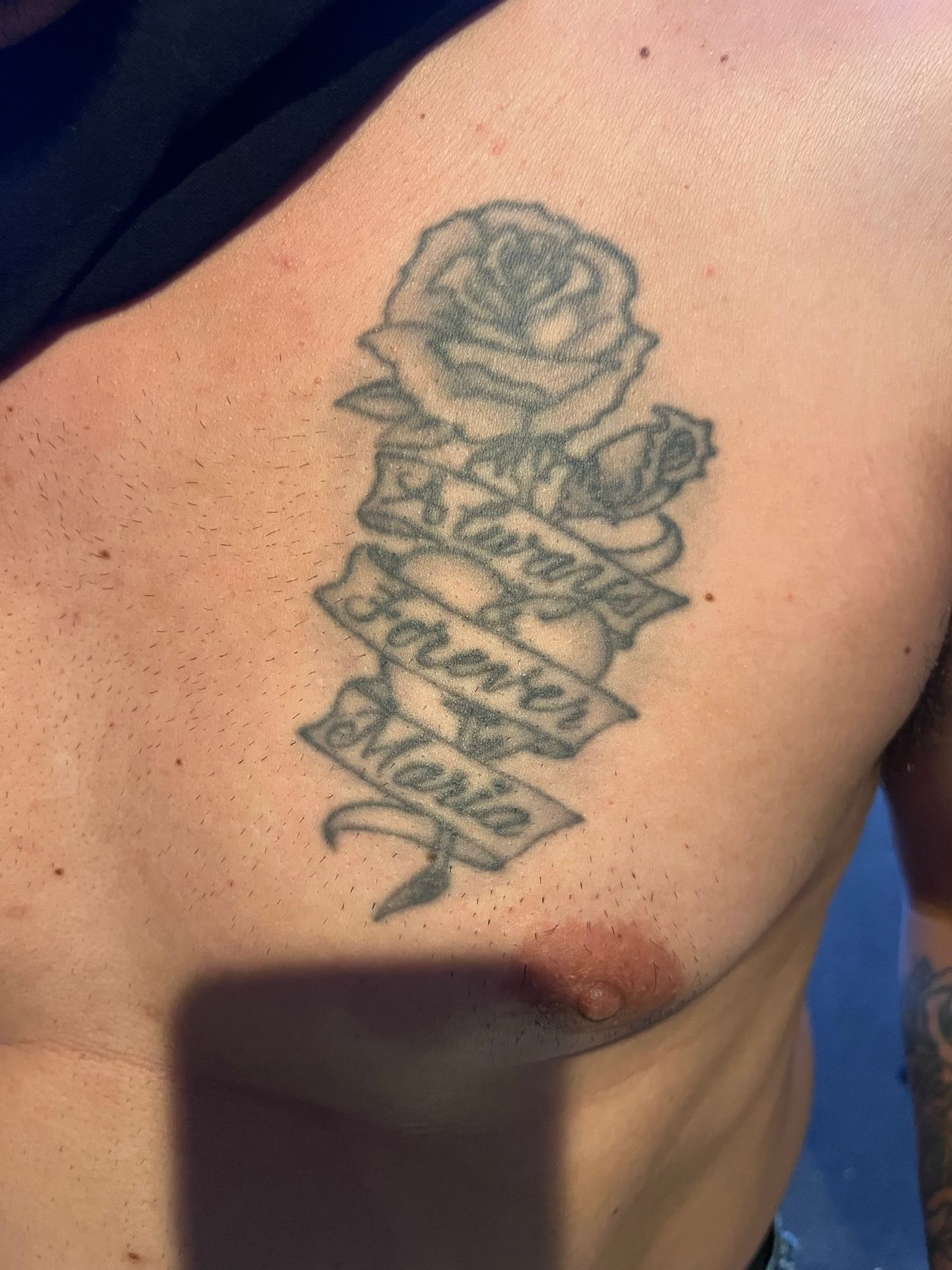 Faded black and grey rose and name-banner chest tattoo before its cover-up at American Ink in Sherman Oaks.