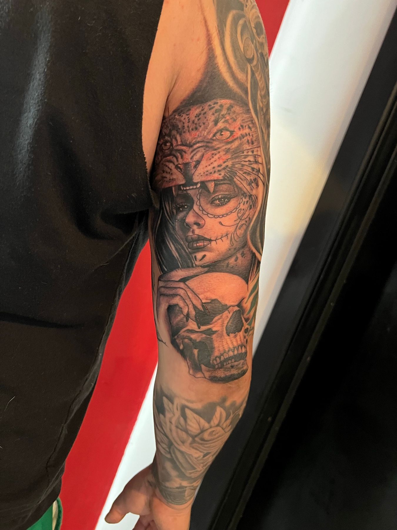 Black and grey chicano style sleeve tattoo of a woman's face with a skull and tiger on a forearm, by American Ink in Sherman Oaks.