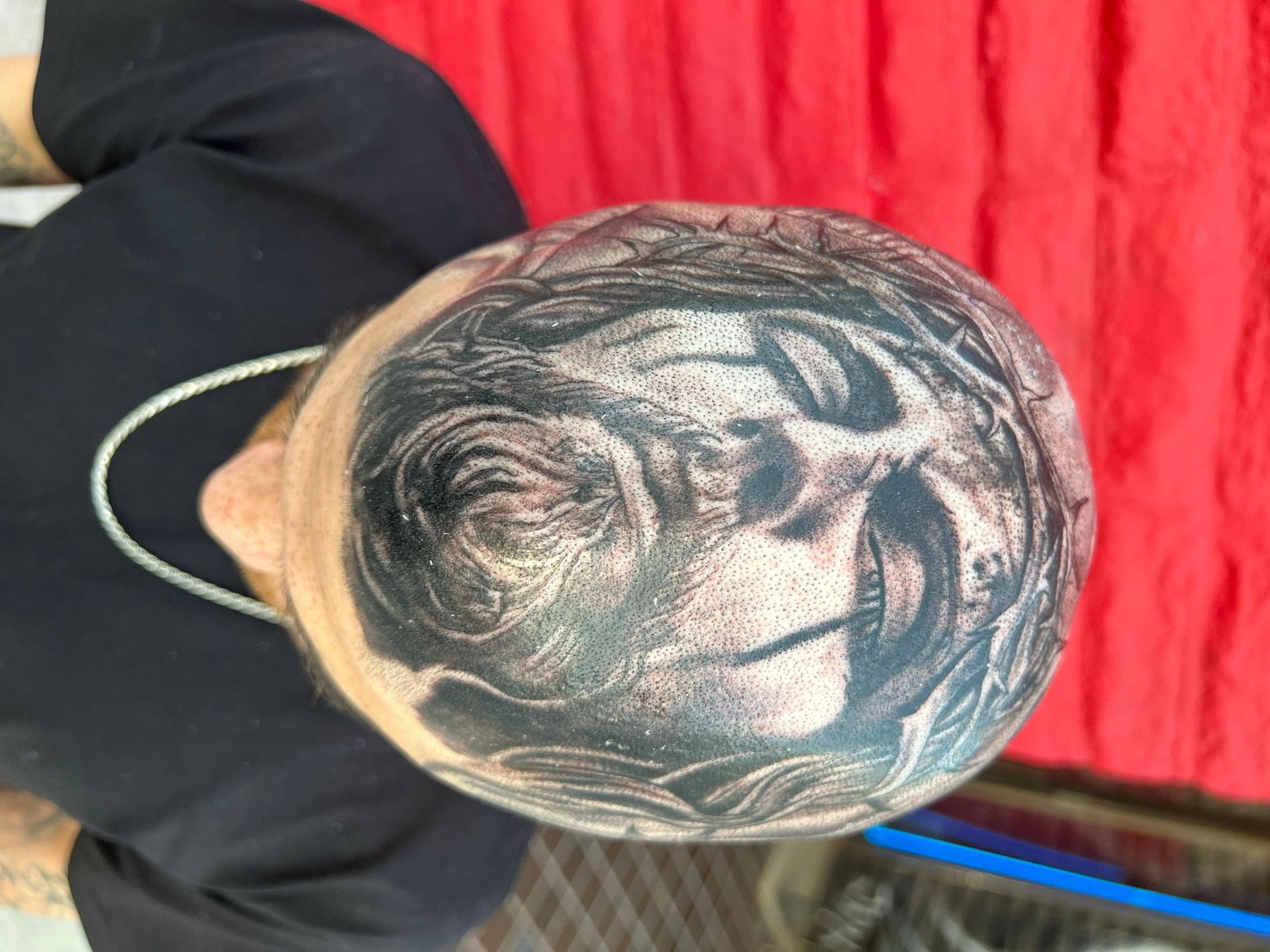 Black and grey realism tattoo of the face of Jesus wearing a crown of thorns covering the scalp, by American Ink in Sherman Oaks.