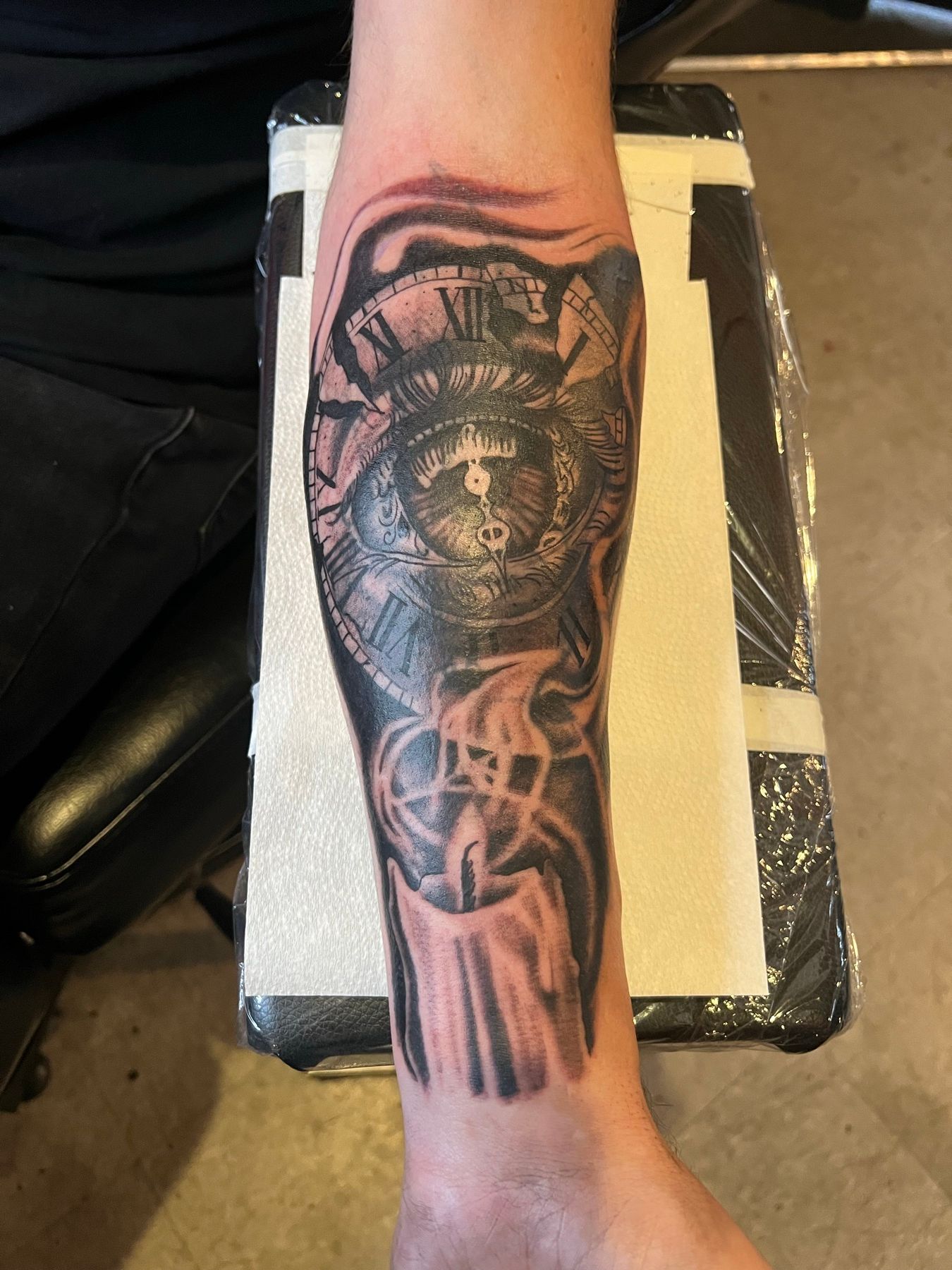 Black and grey tattoo of an antique pocket watch with Roman numerals on a forearm sleeve, by American Ink in Sherman Oaks.
