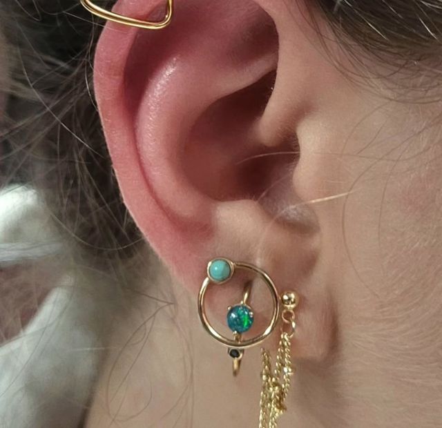 Curated ear with a gold heart helix and opal jewelry, styled at American Ink in Sherman Oaks