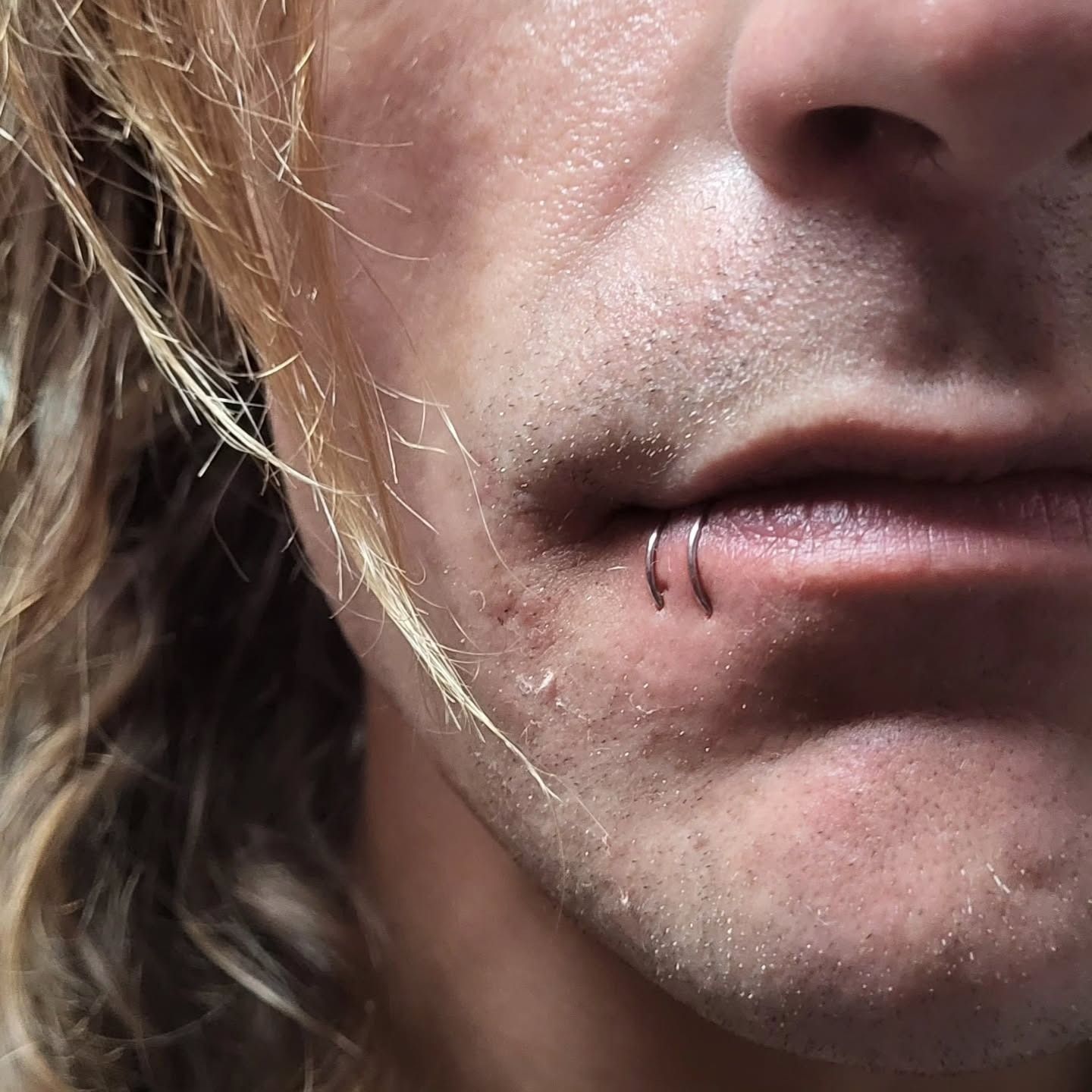 Two steel rings pierced side by side on the lower lip — a spider bites piercing by American Ink, Sherman Oaks.
