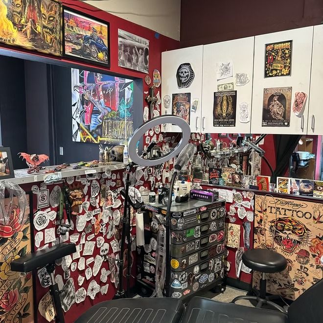 Private tattoo station framed by flash, posters, and stickers inside American Ink