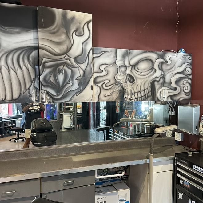 Hand-painted black and grey skull panels above a station mirror inside the studio