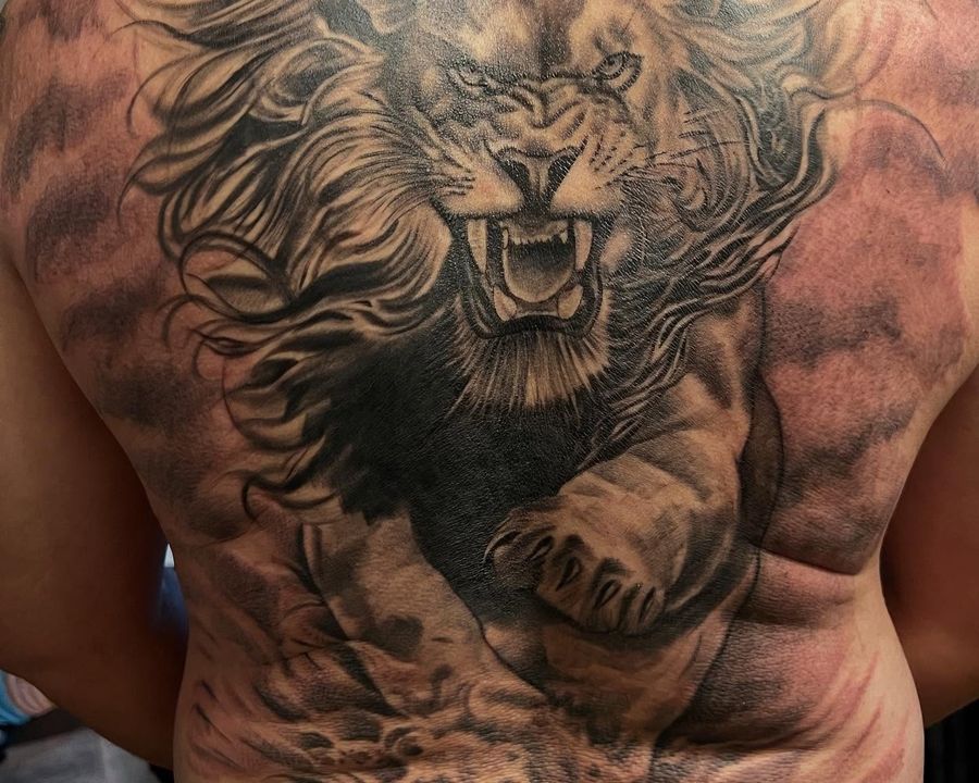 Roaring lion full-back piece in black and grey, tattooed by Josue