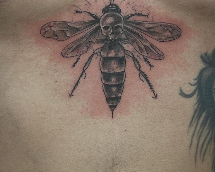 Winged insect chest piece with skull detail in black and grey, tattooed by Josue