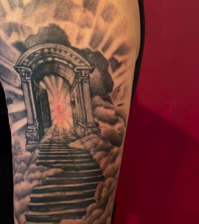 Stairway-to-heaven half-sleeve rising through clouds, tattooed by Josue