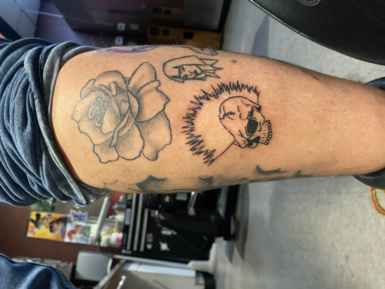 Fine-line black-ink tattoo by Knives of a rose beside a cat skull haloed by sound-wave linework, on a client's upper arm at American Ink in Sherman Oaks.