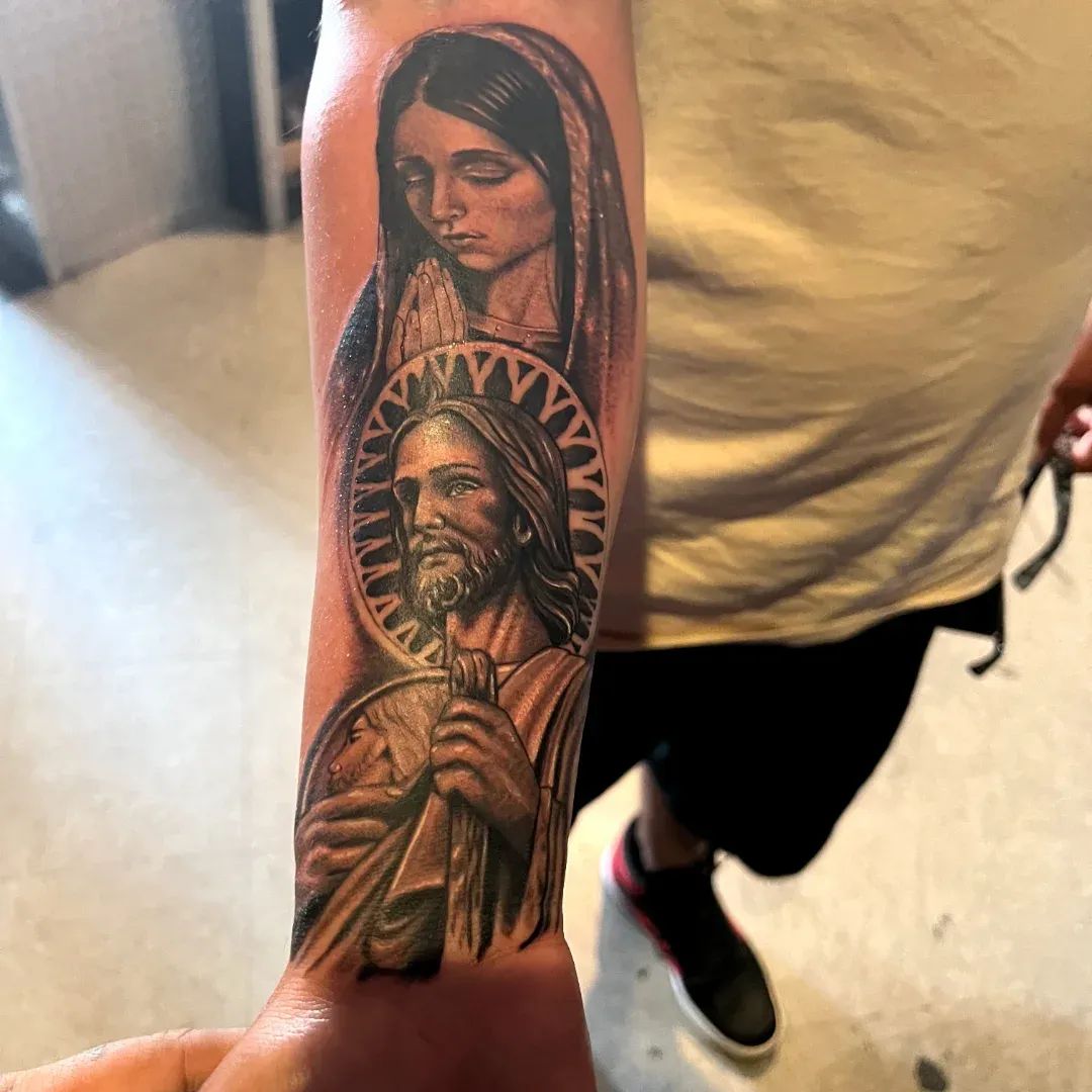 Black and grey religious forearm sleeve with the Virgin Mary praying above San Judas, from the American Ink studio in Sherman Oaks.