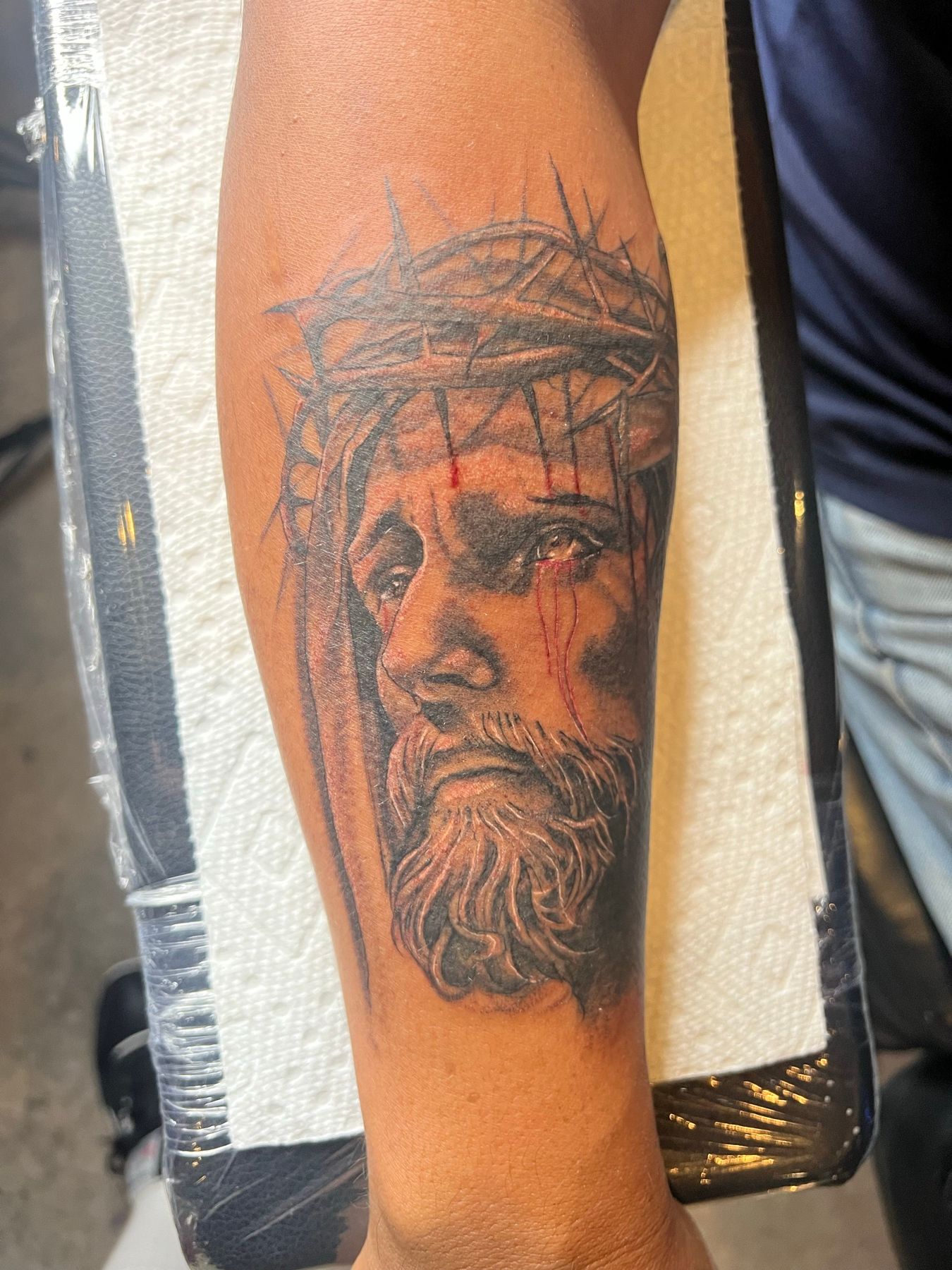 Black and grey forearm tattoo of Jesus Christ wearing the crown of thorns, by American Ink in Sherman Oaks.