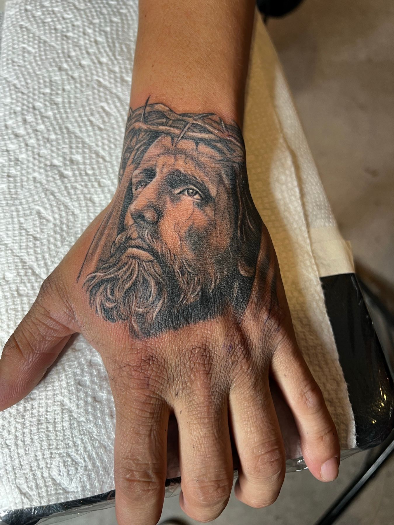 Black and grey hand tattoo of Jesus Christ with the crown of thorns, by American Ink in Sherman Oaks.