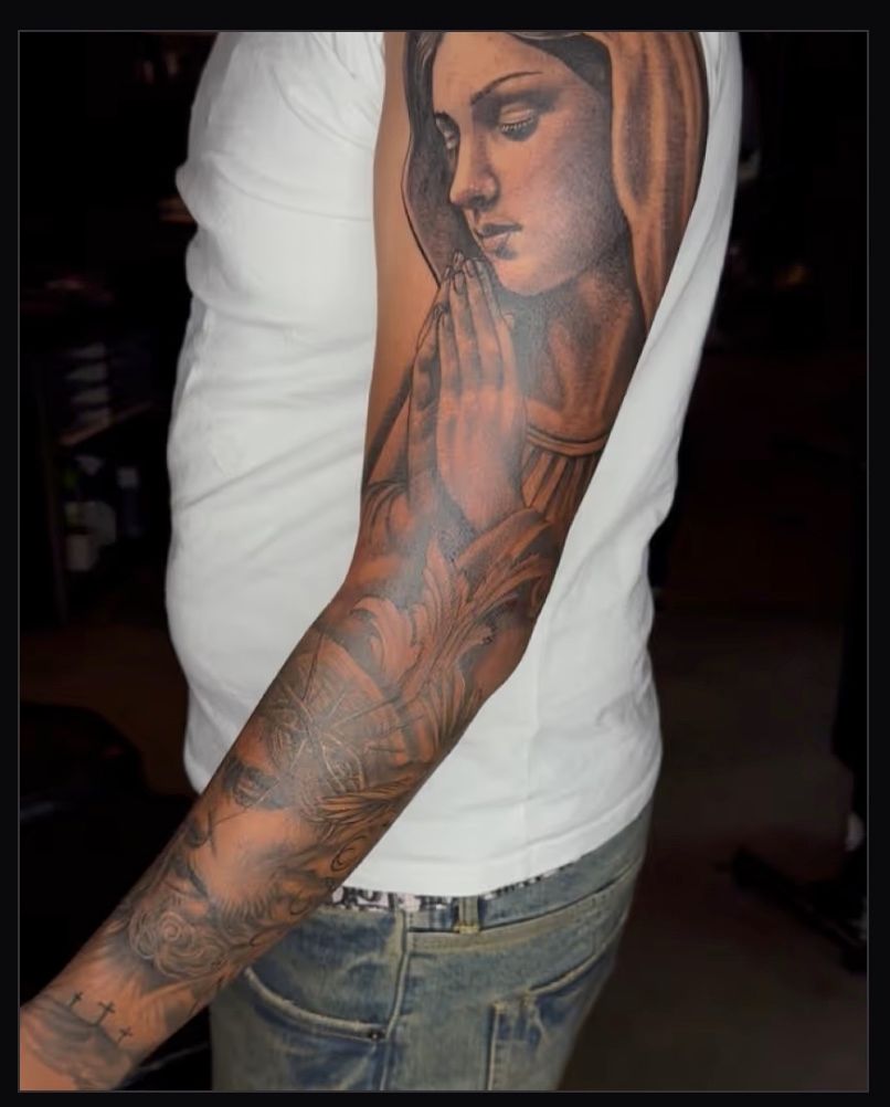Black and grey half-sleeve tattoo of the Virgin Mary praying with clasped hands, by American Ink in Sherman Oaks.