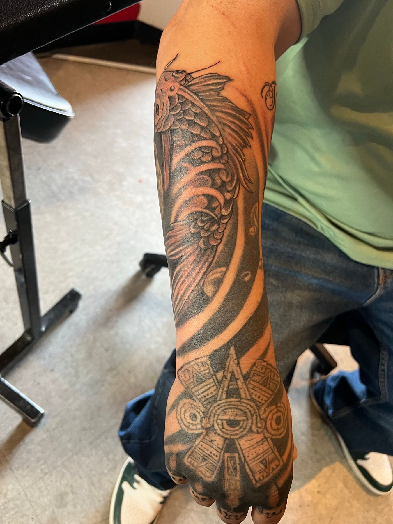 Healed koi fish and waves forearm rework flowing into an Aztec sun stone on the hand, at American Ink in Sherman Oaks.