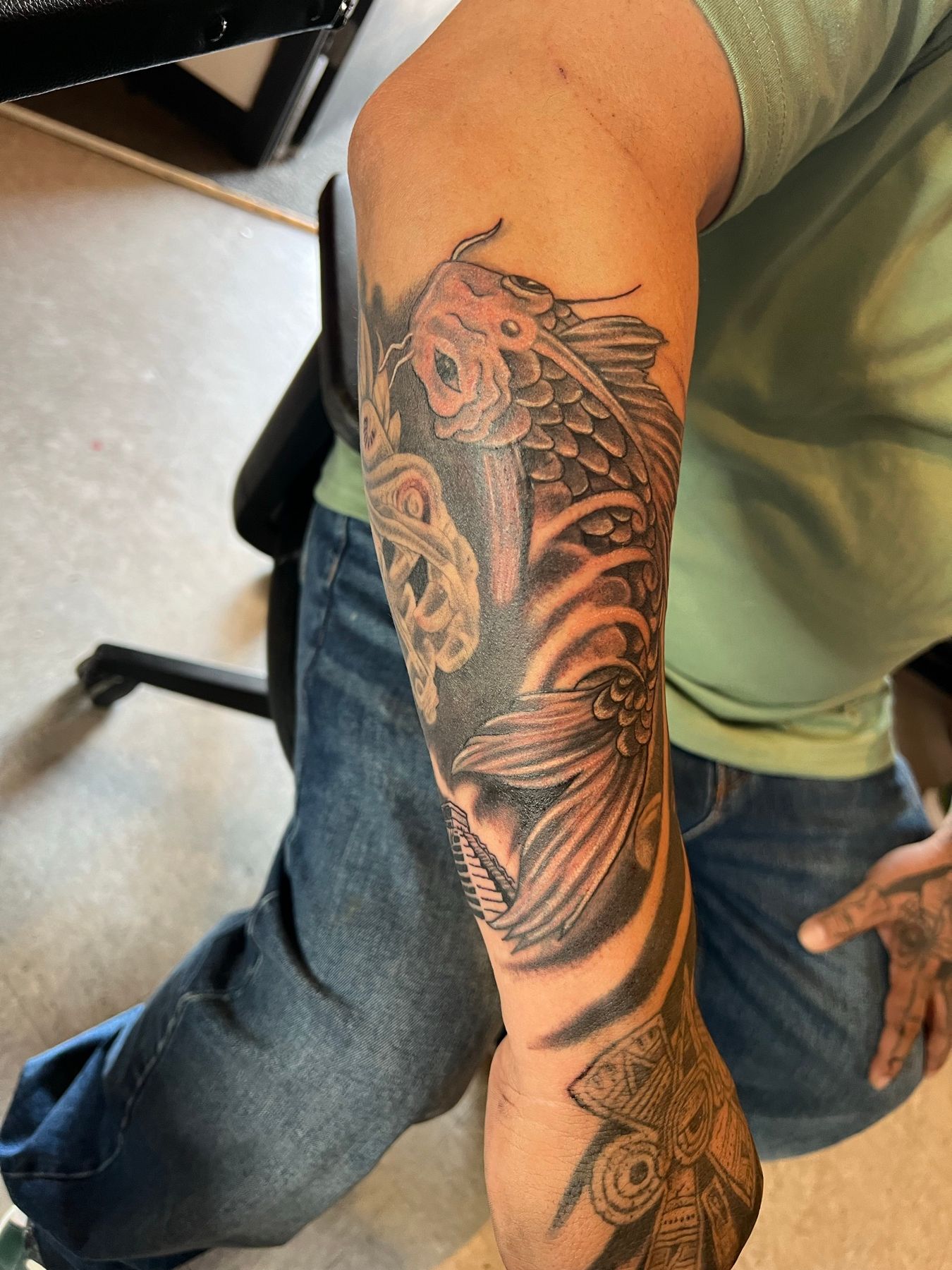 Reworked black and grey koi fish forearm tattoo with rebuilt contrast and added water, by American Ink in Sherman Oaks.