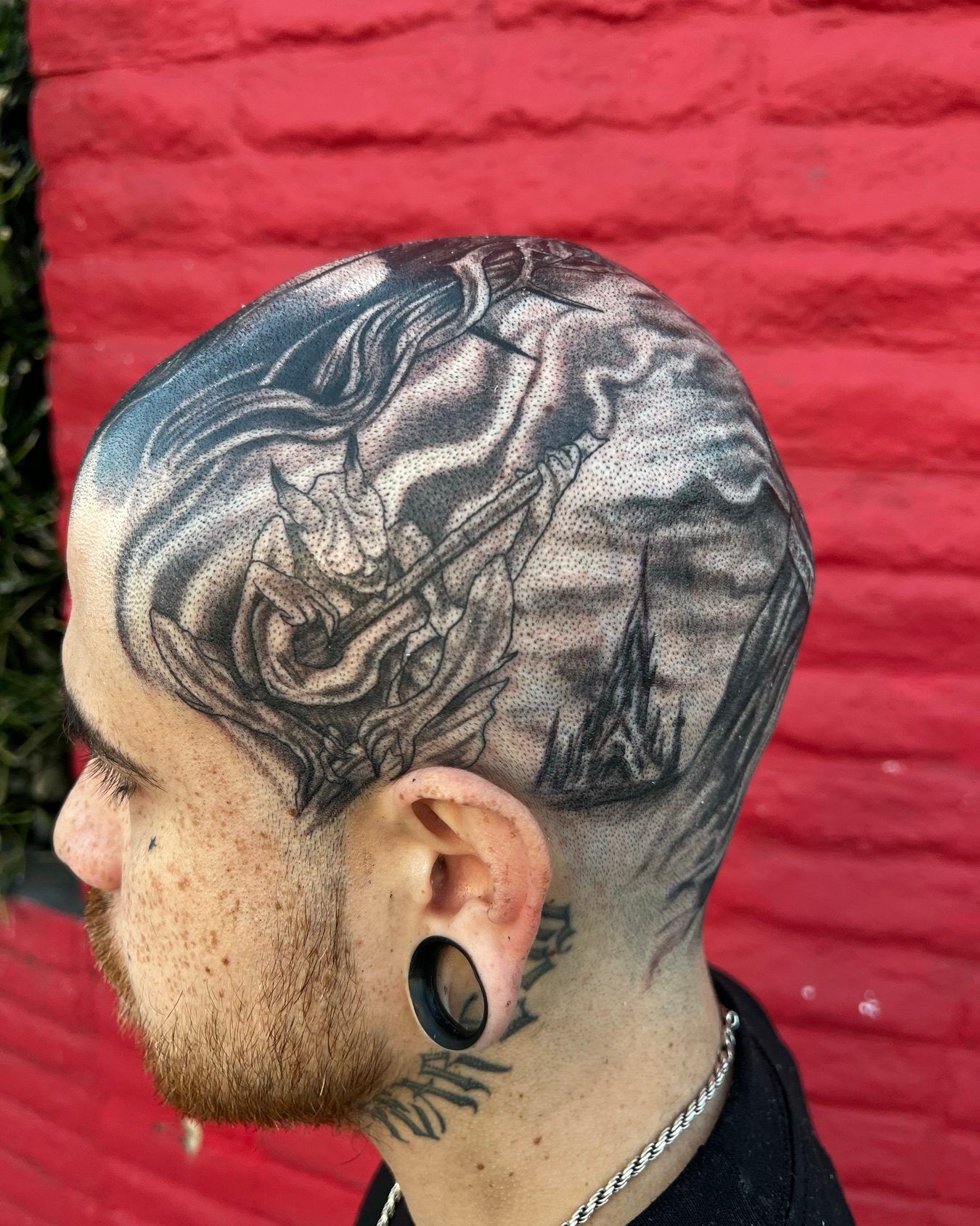 Black and grey scalp and side-of-head tattoo of a horned warrior before a dark castle and spire, by American Ink in Sherman Oaks.