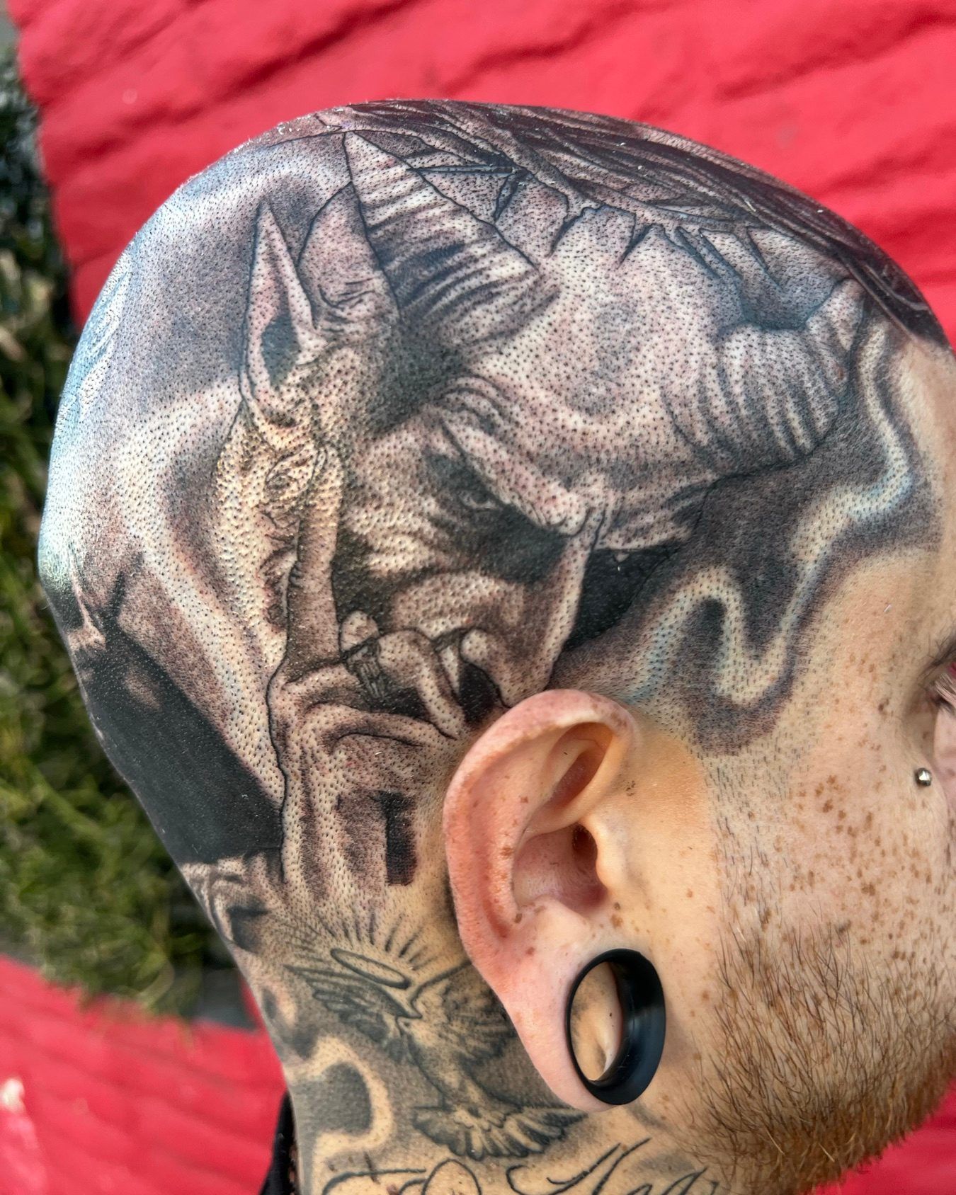 Black and grey scalp tattoo of a horned demon face covering the crown of the head, by American Ink in Sherman Oaks.