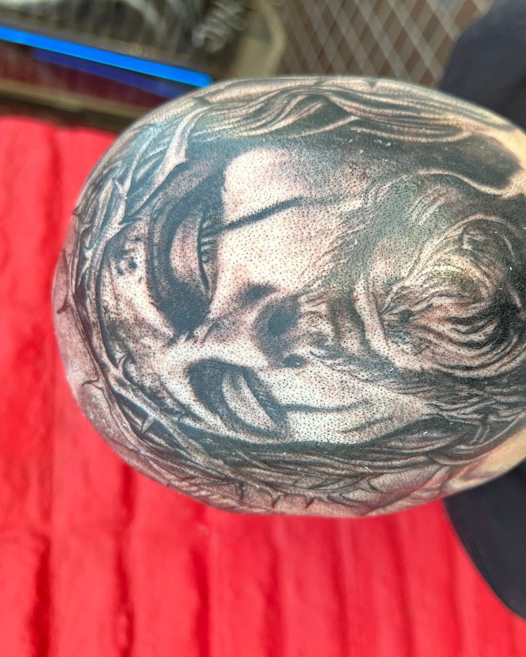 Black and grey scalp tattoo of the face of Jesus wearing the crown of thorns across the top of the head, by American Ink in Sherman Oaks.