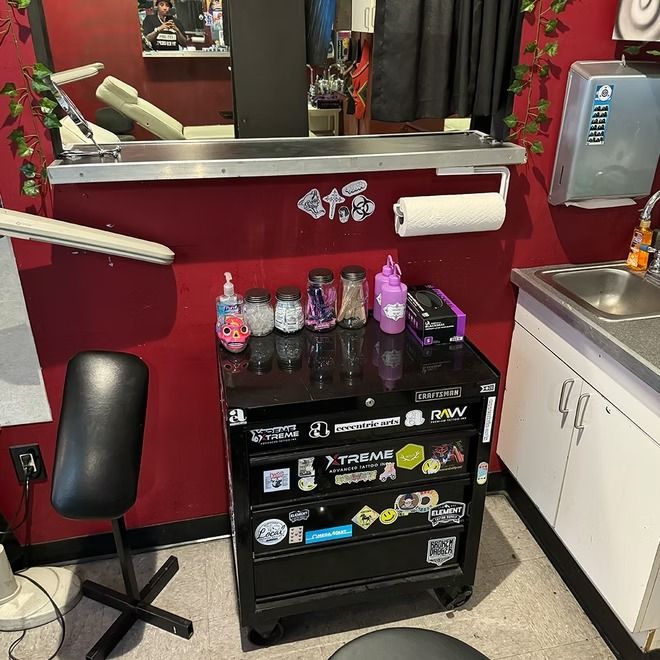 Tidy private workstation with a sticker-covered supply chest and sink at American Ink